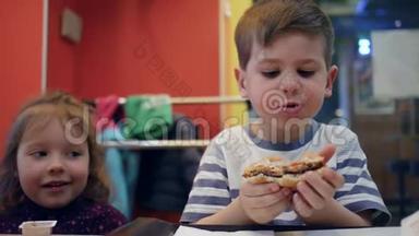 孩子们<strong>边</strong>吃<strong>边</strong>说话，男孩子咀嚼汉堡包，有趣的孩子在快餐店里玩食物，美味的薯<strong>条</strong>